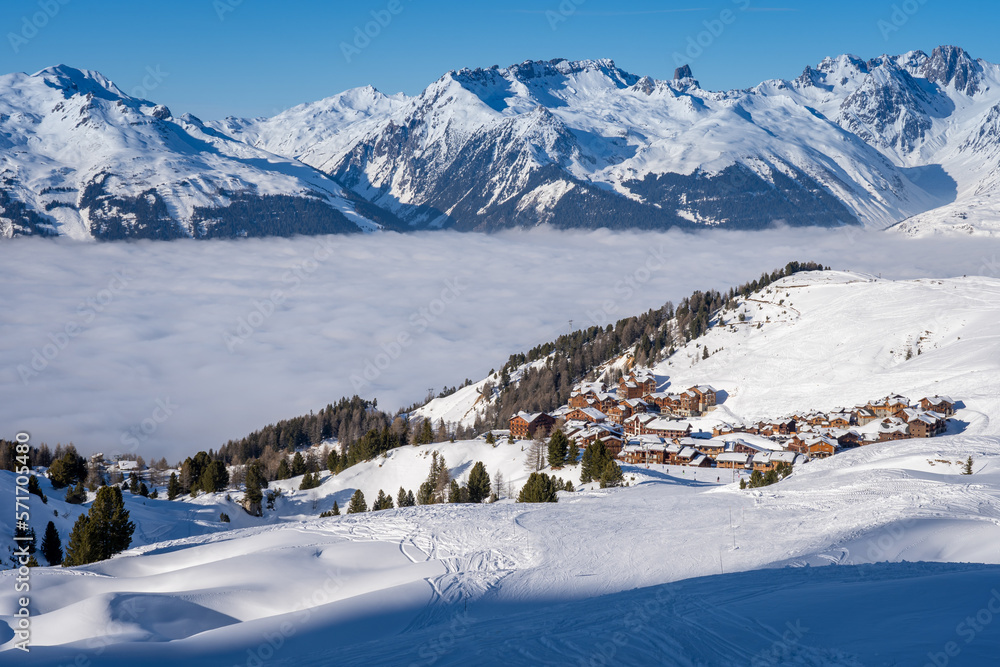 View of Plagne Soleil ski resort in French Savoy Alps. Snowcapped mountains, cloud inversion and apartment buildings