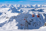 Red gondolas of cable car seen from Bellecote glacier, La Plagne ski resort, France, in winter. Inversion clouds in valley