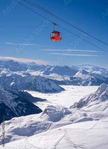 Red gondola of cable car seen from Bellecote glacier, La Plagne ski resort, France,  in winter. Inversion clouds in valley