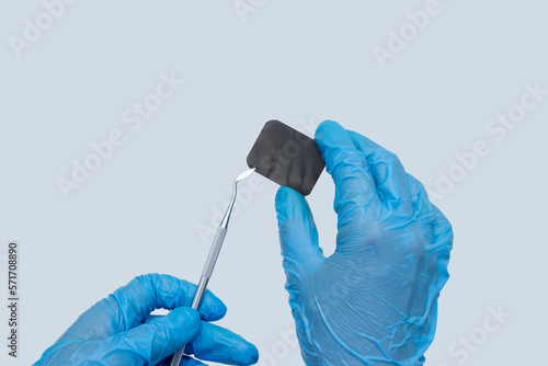 Woman hand holding x-ray of tooth with dentist medical instrument on pastel blue background. Dentist stomatology medical concept. Training oral hygiene.