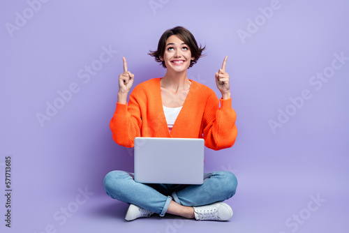 Full length photo of girl wear orange pullover direct fingers up information promo new computer internet shopping isolated on purple color background © deagreez