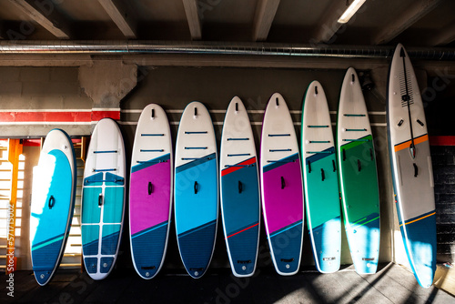 Colorful inflatable stand-up paddle boards SUP by the wall. Surfing and sup boarding equipment close up photo