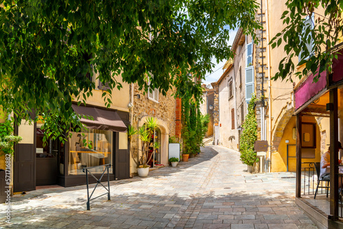 Tela A shady treelined and hilly street or alley of shops and homes in the medieval hilltop village old town of Grimaud, France, in the Provence Cote d'Azur region