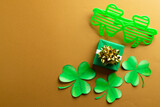 Image of green clover glasses, green clover, green present and copy space on orange background