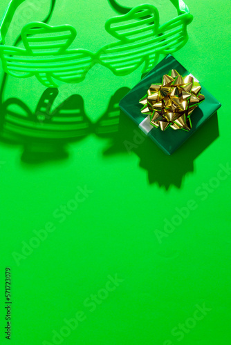 Image of green clover glasses with green present and copy space on green background