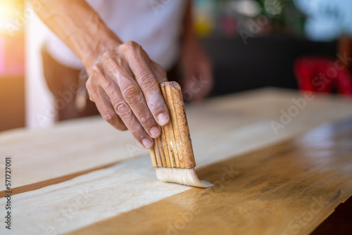 Close-up of a furniture maker varnishing a table photo