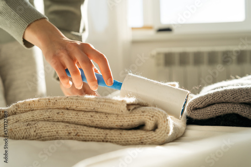 Close-up of a woman using an adhesive roller to remove lint and fluff from a jumper photo