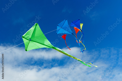 Group of beautiful colorful kites fly over blue sky and clouds