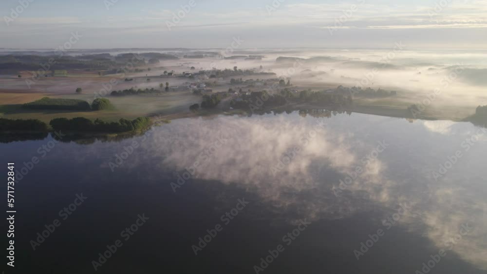 Foggy morning on a beautiful lake surrounded by forests and fields. A small village located near a lake in fog and morning sun. Foggy morning on a beautiful lake surrounded by forests and fields. A small village located near a lake in fog and morning sun.