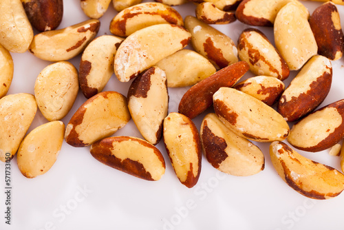 Healthy snack. Shelled roasted Brazil nut seeds on white surface..
