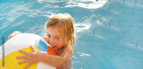 Cute pretty playful happy caucasian blonde two year old girl, child,kid, toddler playing with ball having fun with water outdoor in summer swimming pool.Careless childhood, leisure time lifestyle.