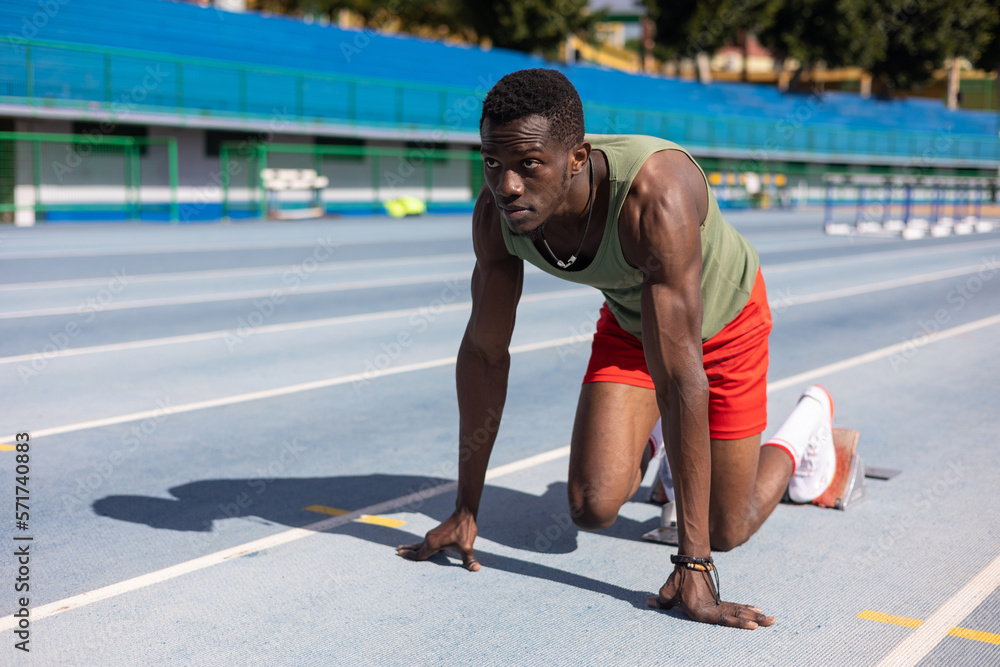 African runner in starting position on athletics track African runner in starting position on athletics track