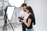 Professional photographer and model looking at pictures on camera in modern studio