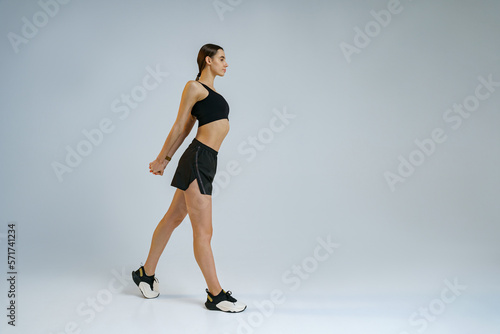 Sporty woman doing warm-up before training session in gym on studio background. High quality photo