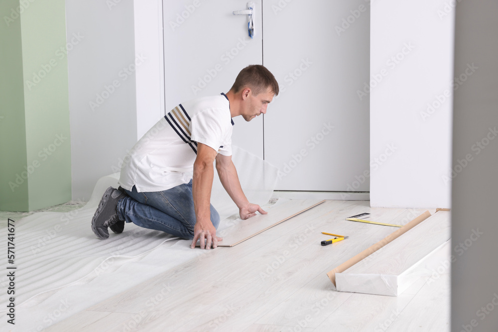 Man installing new laminate flooring in room Man installing new laminate flooring in room