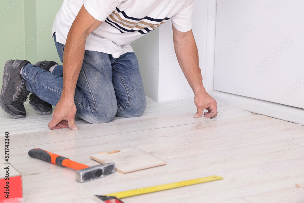 Man installing new laminate flooring indoors, closeup Man installing new laminate flooring indoors, closeup