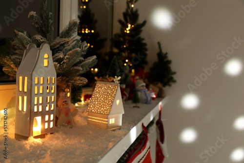 Christmas atmosphere. Beautiful glowing houses, fir trees, artificial snow and toys on window sill indoors. Space for text © New Africa