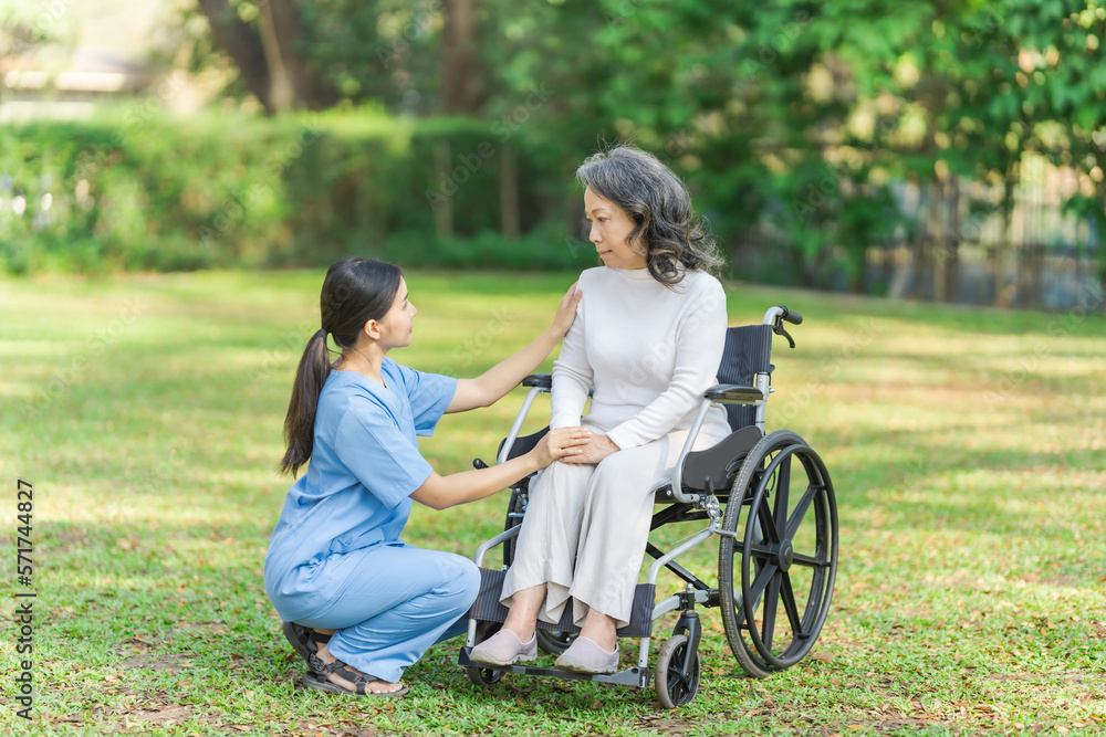 Young asian care helper with asia elderly woman on wheelchair relax together park outdoors to help and encourage and rest your mind with green nature. Young asian care helper with asia elderly woman on wheelchair relax together park outdoors to help and encourage and rest your mind with green nature.
