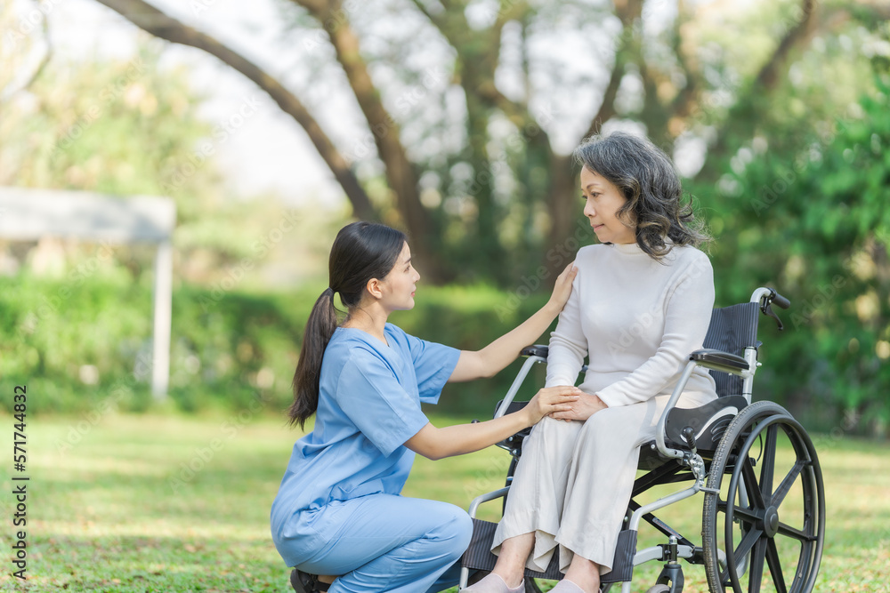 Young asian care helper with asia elderly woman on wheelchair relax together park outdoors to help and encourage and rest your mind with green nature. Young asian care helper with asia elderly woman on wheelchair relax together park outdoors to help and encourage and rest your mind with green nature.
