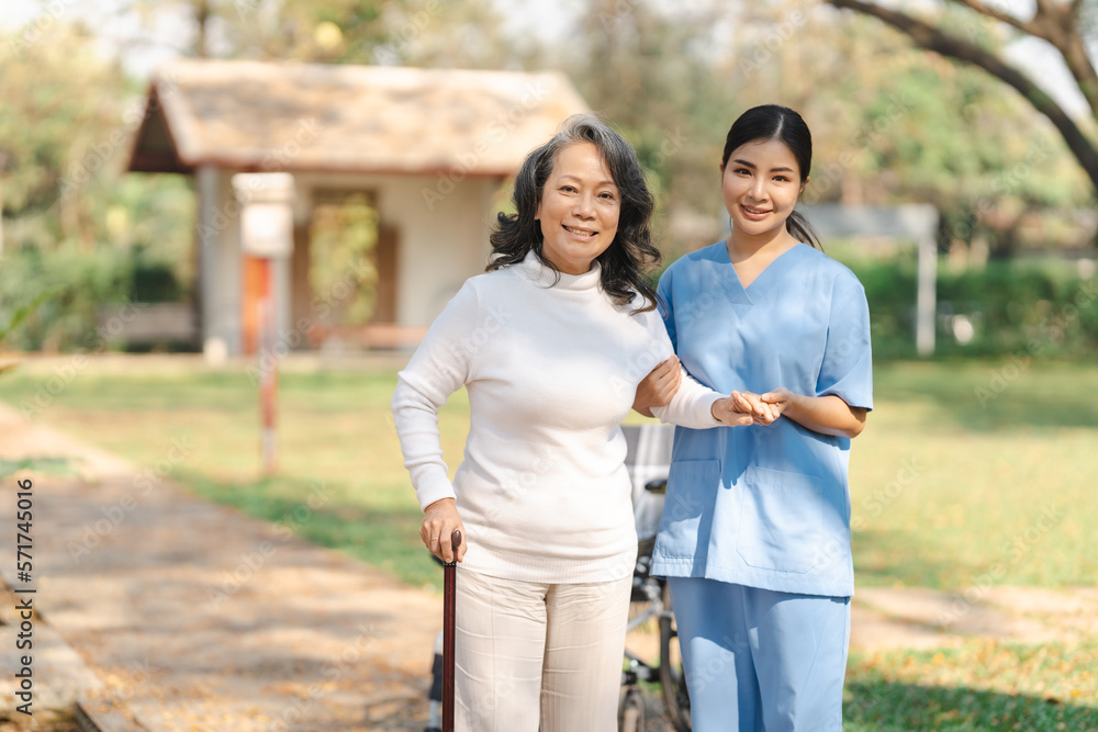 Young asian care helper with asia elderly woman on wheelchair relax together park outdoors to help and encourage and rest your mind. using crutches and cane help support yourself to walk Young asian care helper with asia elderly woman on wheelchair relax together park outdoors to help and encourage and rest your mind. using crutches and cane help support yourself to walk