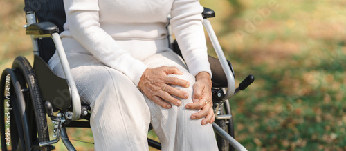 Asian old woman sitting on a wheelchair outdoors in the park have knee pain