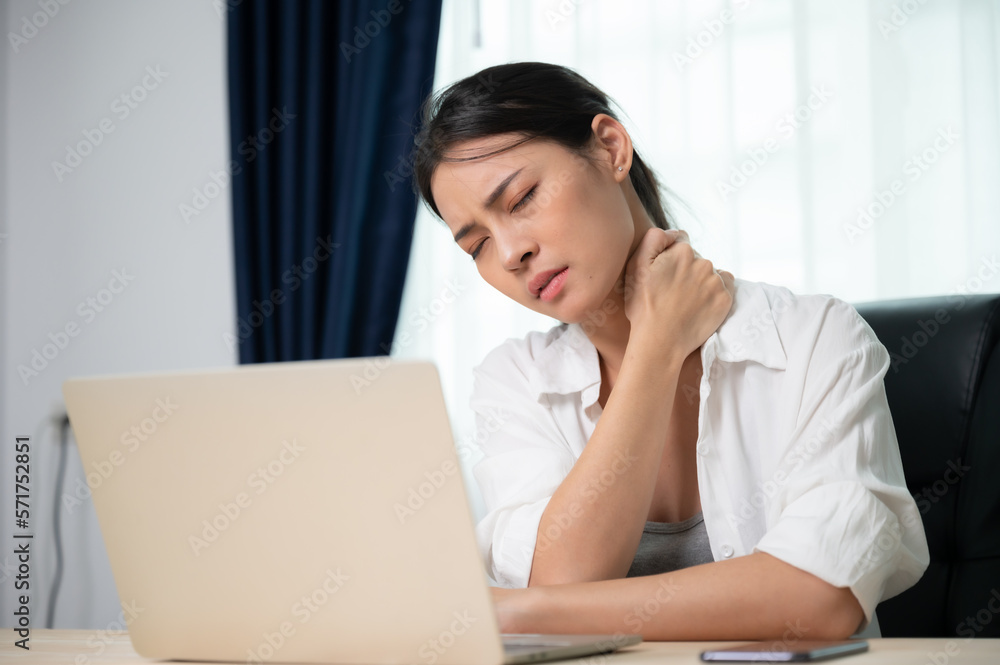 Office syndrome concept. Young asian woman feeling pain in neck and shoulder after working on computer laptop for a long time. She stretches to relax her muscles Office syndrome concept. Young asian woman feeling pain in neck and shoulder after working on computer laptop for a long time. She stretches to relax her muscles