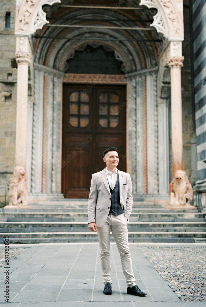 Man in a suit stands in front of the entrance to the church. Bergamo, Italy