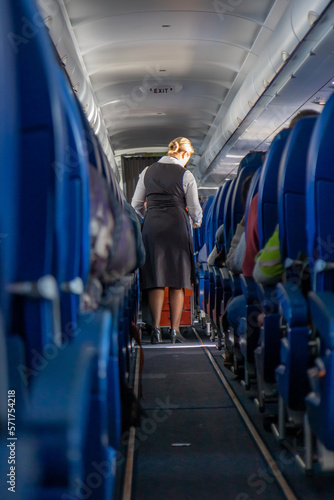 The stewardess serve refreshments on board the aircraft. An view at the corridor of the airplane.