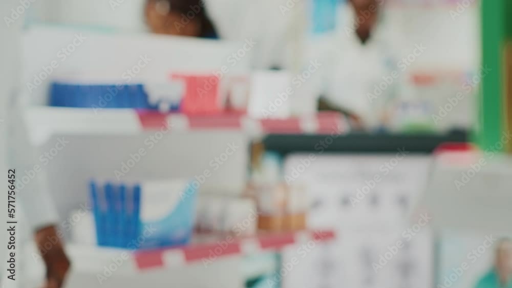 African american client looking at drugs on shelves, buying medicaments and healthcare products from drugstore. Young customer taking pills or vitamins from racks. Handheld shot. African american client looking at drugs on shelves, buying medicaments and healthcare products from drugstore. Young customer taking pills or vitamins from racks. Handheld shot.