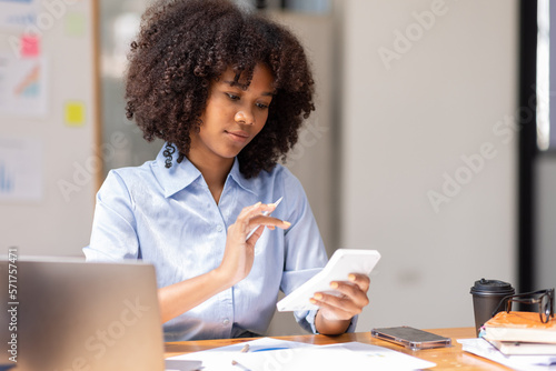 Accountant Young african businesswoman in afro hairstyle Using Calculator For documents Accounting financial sitting at computer in workplace office 