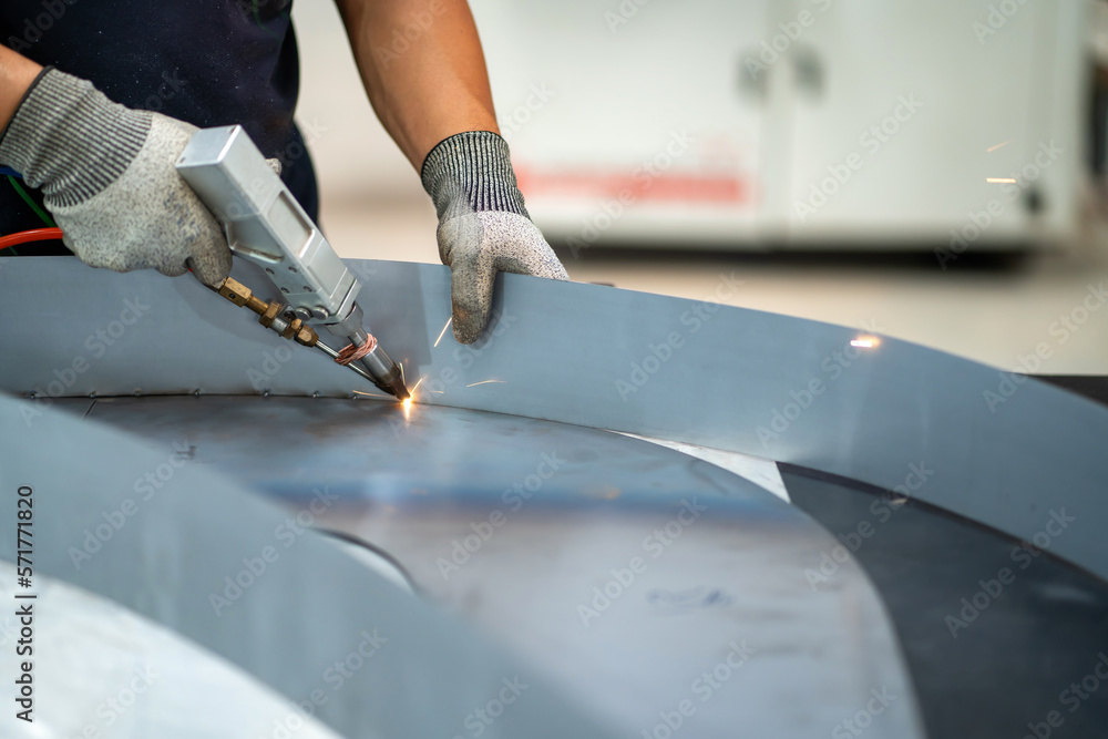 Steel handles are welded with argonarc welding. Man wearing argonarc