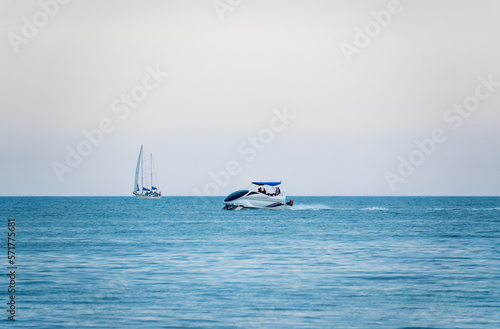 Two Sailing yachts in the blue calm sea and landing plane in the sky