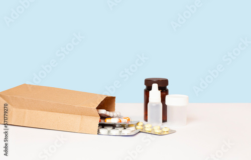 paper bag with pills and medical bottles on the table on a blue background