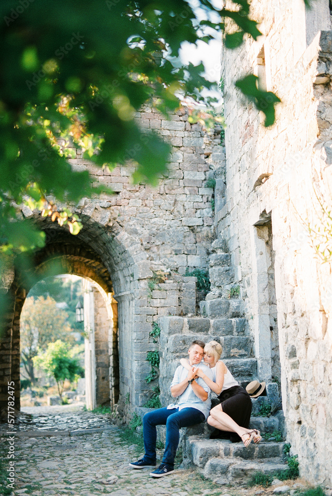 Woman hugs a man while sitting on the stone steps of the castle