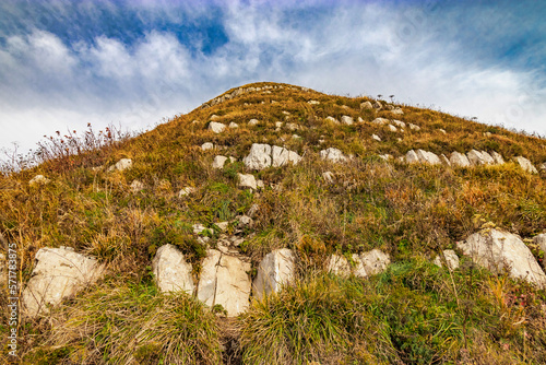 Large stones on the slope of Mount Peus. Mountain landscape with beautiful Caucasian nature. Panoramic view of the Caucasus mountains. Dry grass on the slope of a high mountain.  photo