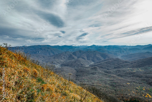 View of the mountain range under a cloudy sky. Panoramic view of the Caucasus mountains. Mountain landscape with beautiful Caucasian nature. Landscape of a mountain range on an autumn morning.