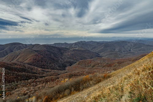 Mountain landscape with beautiful Caucasian nature. View of the mountain range under a cloudy sky. Panoramic view of the Caucasus mountains. Landscape of a mountain range on an autumn morning. 