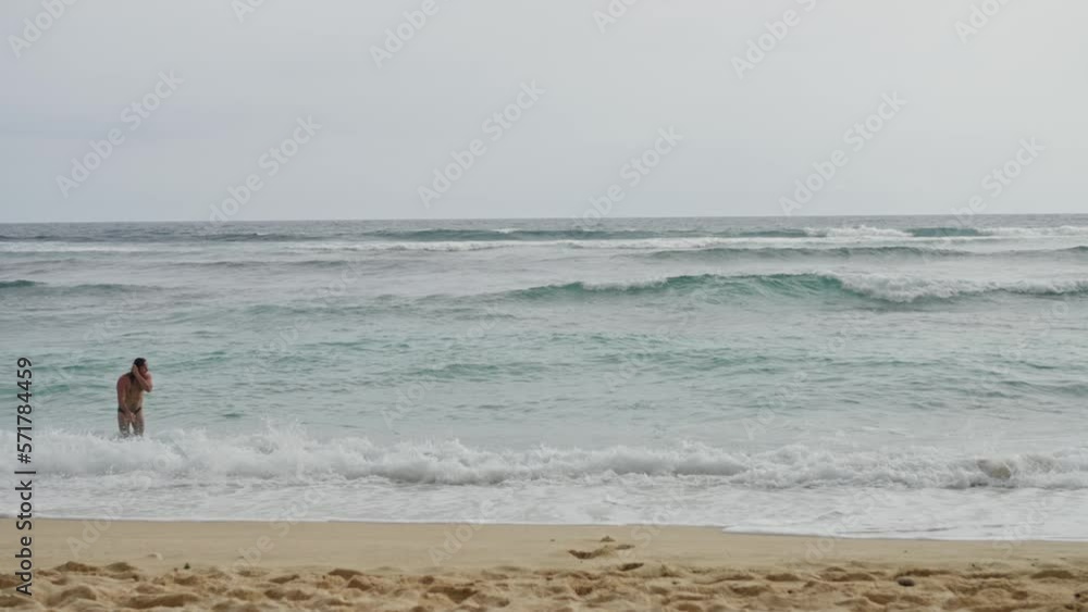 A Beautiful Landscape, a Deserted Beach, far away a Handsome Naked Man Approaches the Ocean and Dives into the Water, Slow motion A Beautiful Landscape, a Deserted Beach, far away a Handsome Naked Man Approaches the Ocean and Dives into the Water, Slow motion