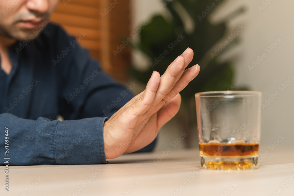 Alcoholism, depressed asian young man refuse, push out alcoholic beverage glass, drink whiskey, sitting alone at night. Treatment of alcohol addiction, having suffer abuse problem alcoholism concept. Alcoholism, depressed asian young man refuse, push out alcoholic beverage glass, drink whiskey, sitting alone at night. Treatment of alcohol addiction, having suffer abuse problem alcoholism concept.