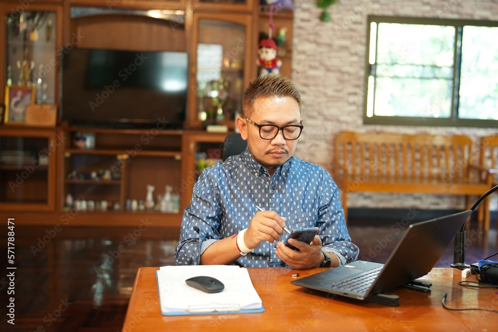 Fototapeta premium Middle-aged man playing on the phone at work desk