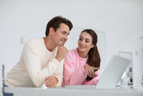 Cheerful couple at home using laptop together.