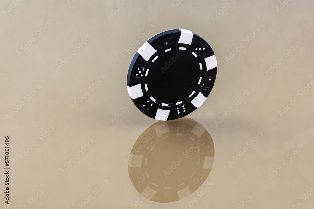 A black casino chip stands on the reflecting surface A black casino chip stands on the reflecting surface