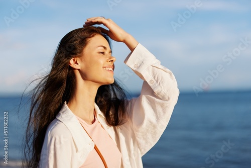 Woman portrait smile with teeth freedom on vacation walking on the beach by the ocean in Bali sunset, happy travel and vacation, sunset light, flying hair, skin and hair care concept in the sun