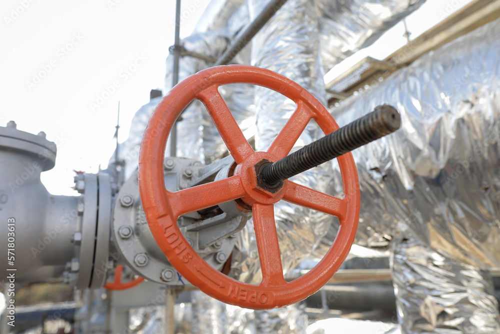 Shallow depth of field details with a metallic pipe valve used to open or close the hot water debit inside a big pipeline. Shallow depth of field details with a metallic pipe valve used to open or close the hot water debit inside a big pipeline.