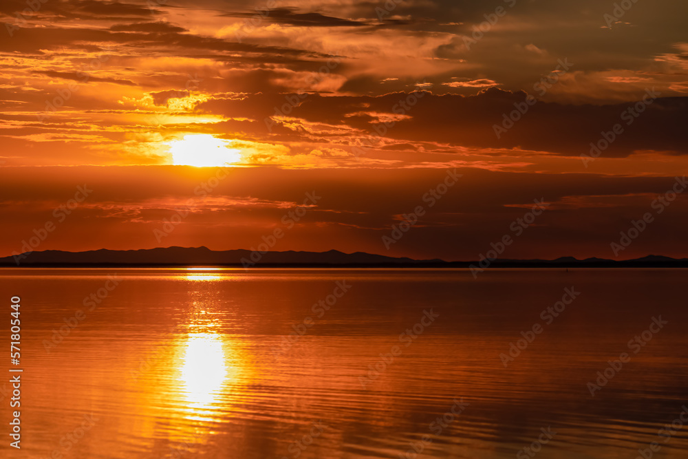 Scenic sunrise view of beautiful water reflections in lake of Bonneville Salt Flats, Wendover, Western Utah, USA, America. Dreamy clouds mirroring on the water surface creating romantic atmosphere
