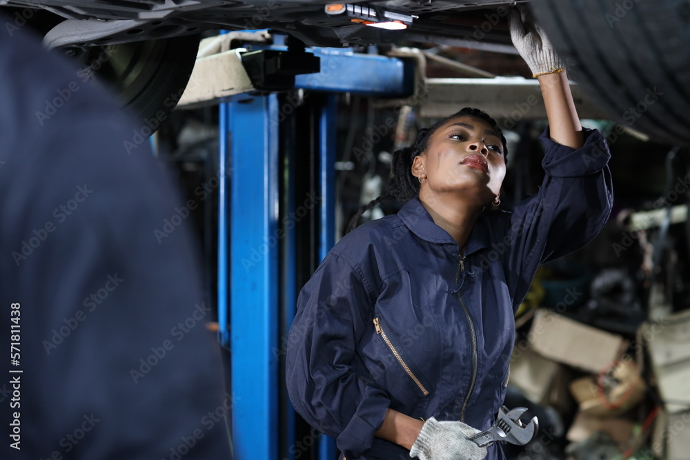 Group of car mechanic in uniform checking maintenance a lifted car service with clipboard at repair garage station. Worker holding wrench and fixing breakdown vehicle. Car repair service concept