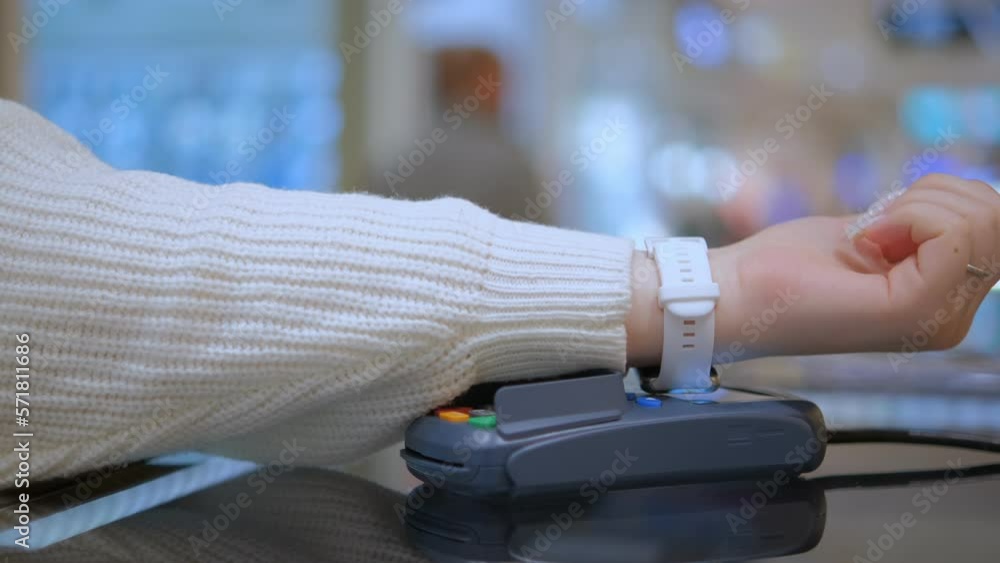 Wireless payment by smart watch using e wallet on pos terminal or card reader. Female buyer hand pays electronic cashless money at shopping place close up indoors Wireless payment by smart watch using e wallet on pos terminal or card reader. Female buyer hand pays electronic cashless money at shopping place close up indoors