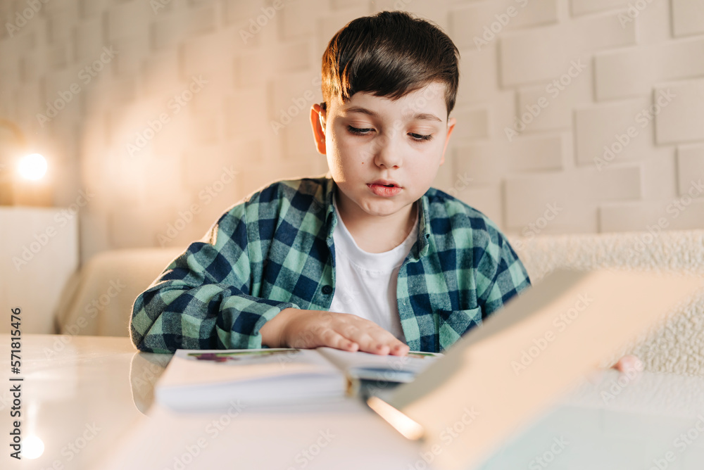 Kid school boy doing homework at home. Remote education. Reading writing subjects Kid school boy doing homework at home. Remote education. Reading writing subjects