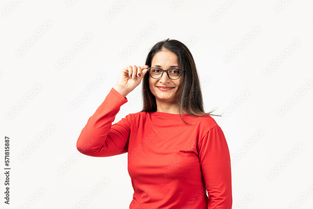 Mid aged Indian woman is choosing new glasses or adjusting spectacles over white background Mid aged Indian woman is choosing new glasses or adjusting spectacles over white background