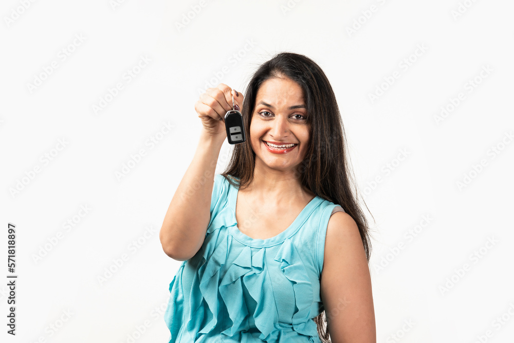 Mid aged Indian woman giving showing close up car key isolated on white background Mid aged Indian woman giving showing close up car key isolated on white background